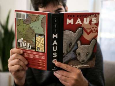 A person holds open a copy of the graphic novel, "Maus"