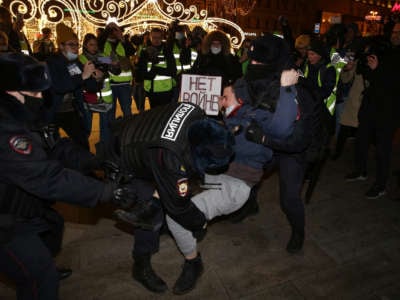 Police officers detain a man holding a placard reading "No war" during a protest at Pushkinskaya Square on February 24, 2022, in Moscow, Russia.