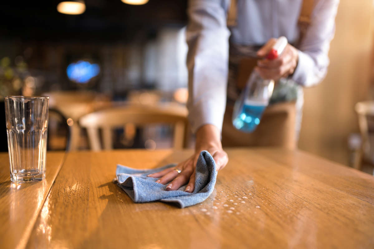 Waitress cleaning tables with disinfectant in a cafe.