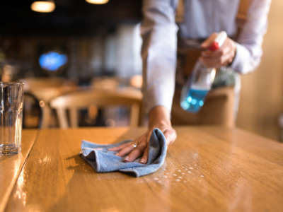 Waitress cleaning tables with disinfectant in a cafe.