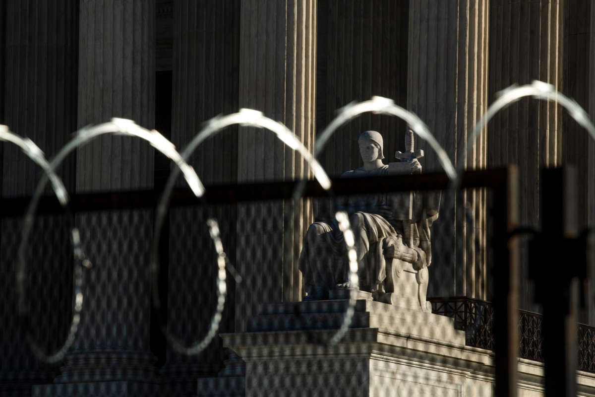 The Authority of Law statue is seen through razor wire in front of the U.S. Supreme Court on February 8, 2021.