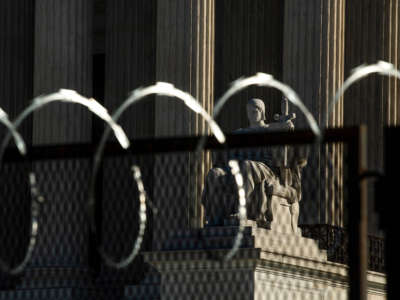 The Authority of Law statue is seen through razor wire in front of the U.S. Supreme Court on February 8, 2021.