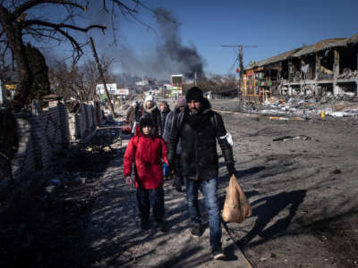 People walk amid destruction as they evacuate from a contested frontline area between Bucha and Irpin on March 10, 2022, in Irpin, Ukraine.