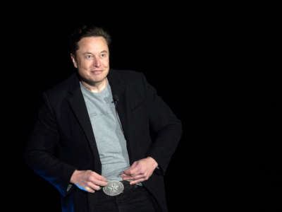 Elon Musk shows his Texas belt buckle as he speaks during a press conference at SpaceX's Starbase facility near Boca Chica Village in South Texas on February 10, 2022.