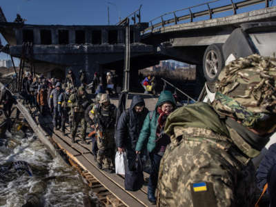 Residents of Irpin and Bucha flee fighting via a destroyed bridge on March 10, 2022, in Irpin, Ukraine.