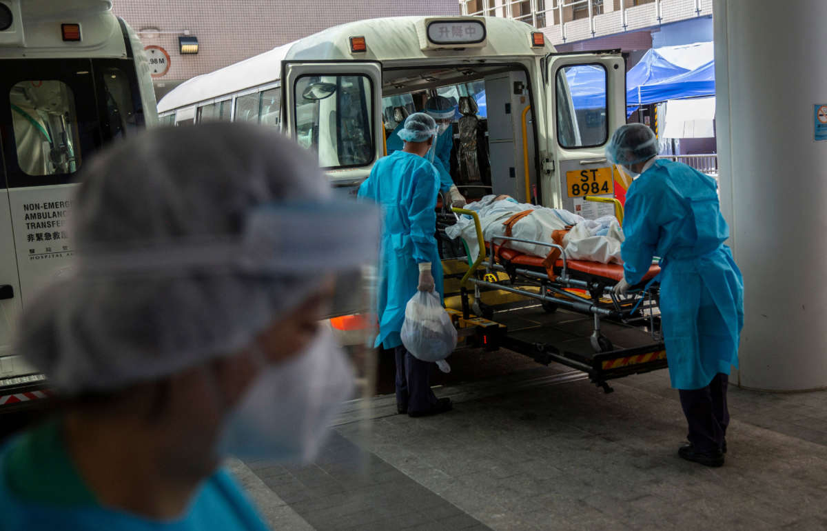 A person is transferred onto a bus outside Queen Elizabeth Hospital in Hong Kong on March 10, 2022, as the government announced the hospital will be used only for COVID-19 patients.