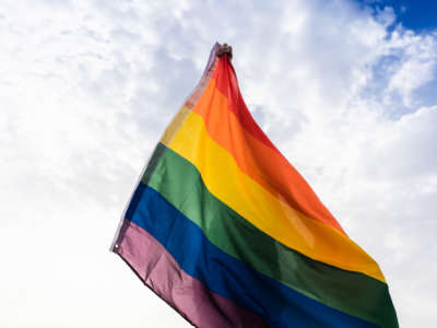 Person holds up LGBTQ flag