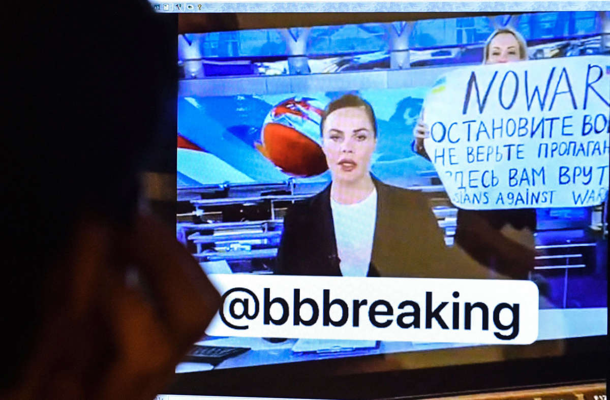 A man looks at a computer screen watching a dissenting Russian Channel One employee entering Ostankino on-air TV studio during Russia's most-watched evening news broadcast, holding up a poster which reads as "No War" and condemning Moscow's military action in Ukraine in Moscow on March 14, 2022.