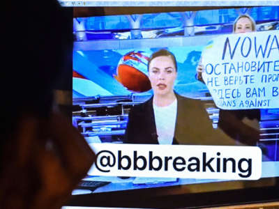 A man looks at a computer screen watching a dissenting Russian Channel One employee entering Ostankino on-air TV studio during Russia's most-watched evening news broadcast, holding up a poster which reads as "No War" and condemning Moscow's military action in Ukraine in Moscow on March 14, 2022.