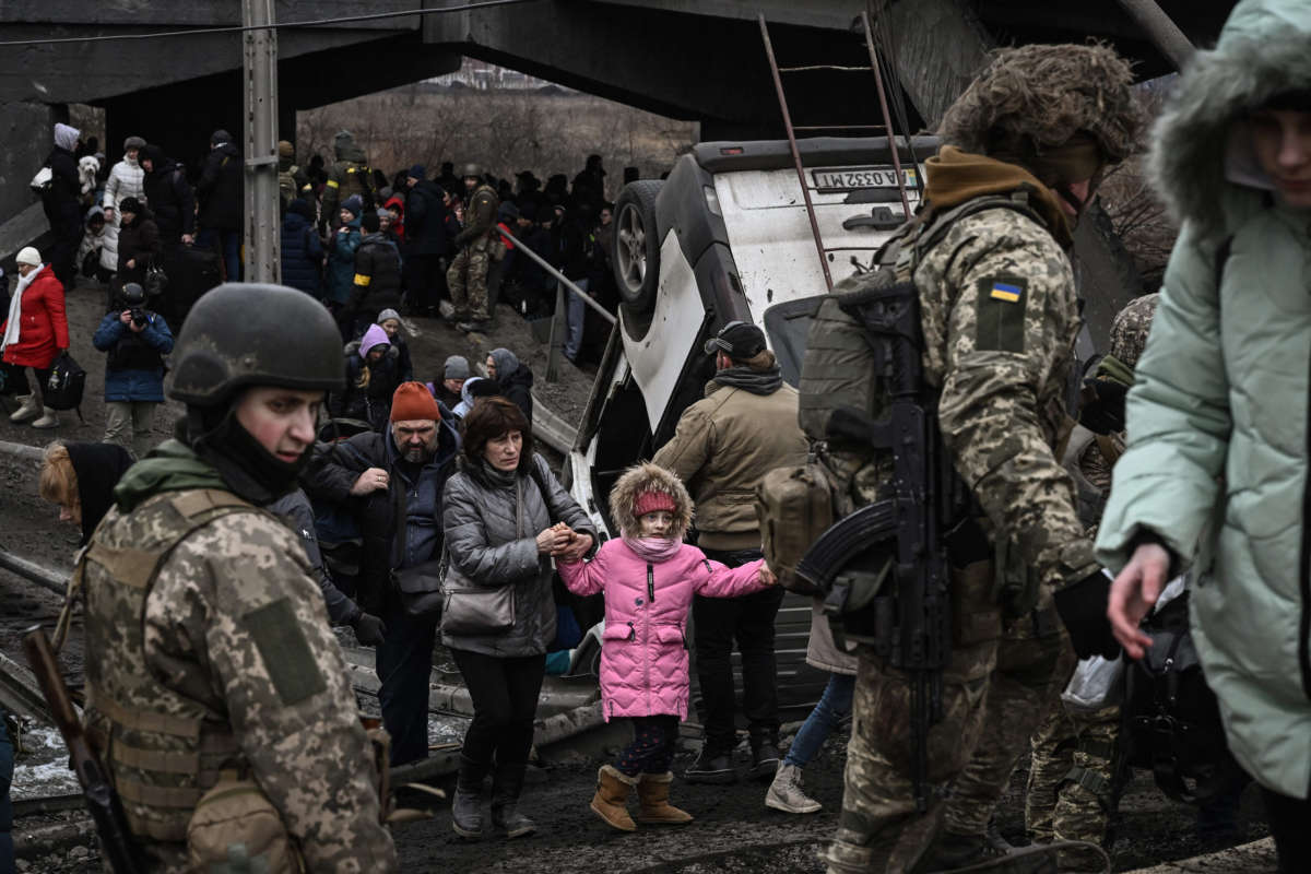 People cross a destroyed bridge as they evacuate the city of Irpin, northwest of Kyiv, during heavy shelling and bombing on March 5, 2022, 10 days after Russia launched a military invasion on Ukraine.