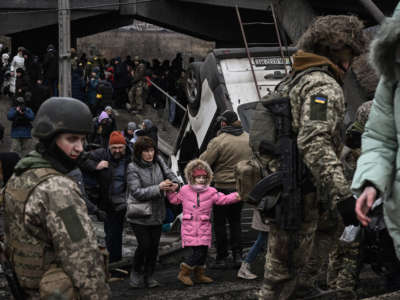 People cross a destroyed bridge as they evacuate the city of Irpin, northwest of Kyiv, during heavy shelling and bombing on March 5, 2022, 10 days after Russia launched a military invasion on Ukraine.