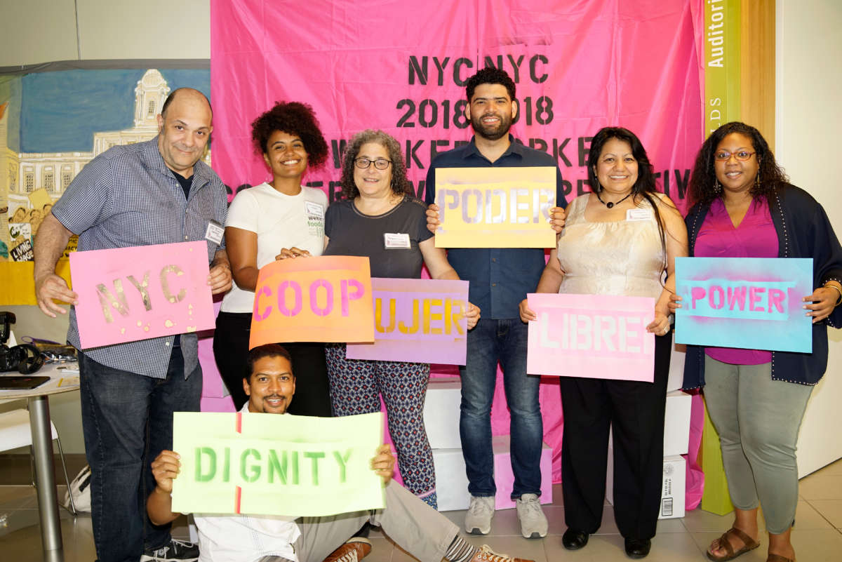 Attendees pose with signs at the NYC 2018 Worker Cooperative Conference.