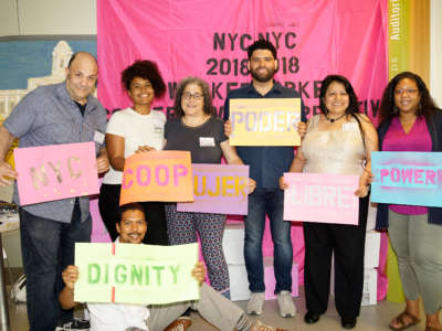 Attendees pose with signs at the NYC 2018 Worker Cooperative Conference.