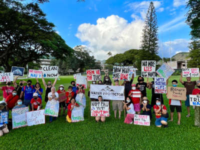 Oʻahu Water Protectors gather with signs protesting the U.S. Navy and the Red Hill bulk fuel station.