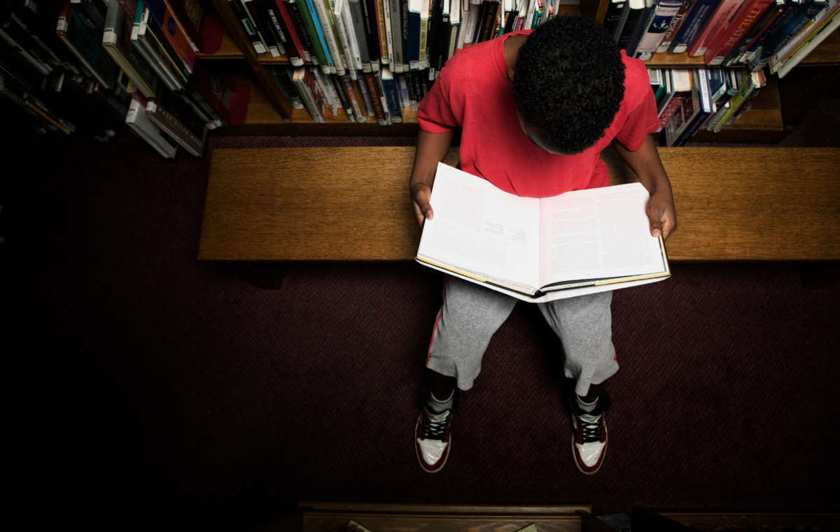 Top-down view of child reading a book in a library