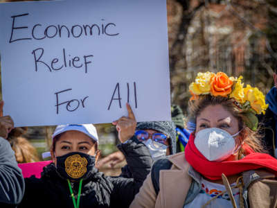 Protester holding a sign saying "Economic Relief for All"