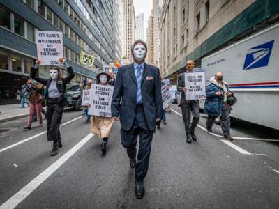 Protesters dressed as masked bankers march forward
