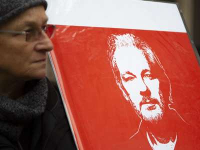 Protester for Julian Assange holds up sign