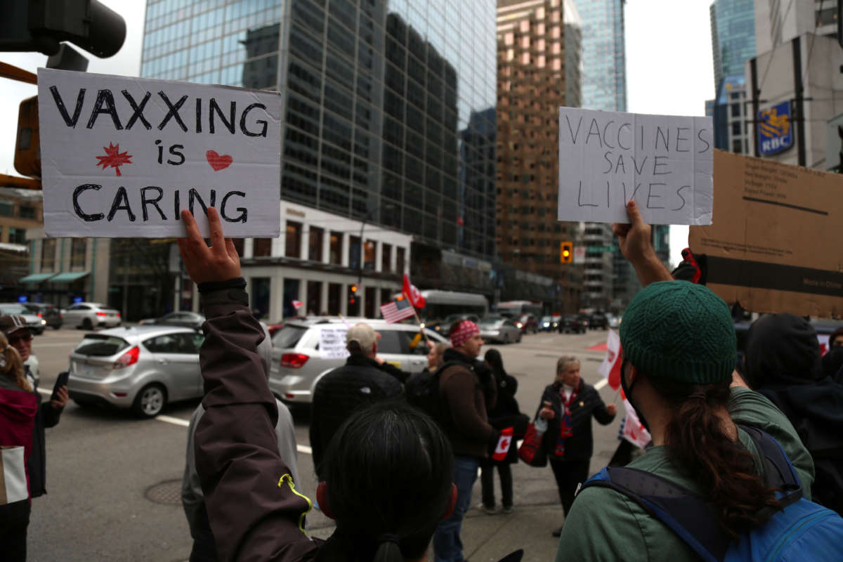 Counterprotestors hold signs during a demonstration against mandates related to COVID-19 vaccines and restrictions in downtown Vancouver, Canada, on February 5, 2022.