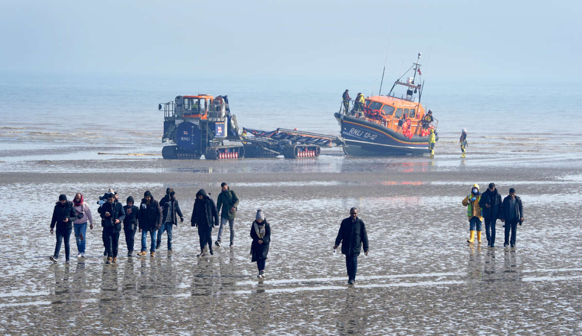 A group of people thought to be migrants are guided up the beach after being brought in to Dungeness, Kent, onboard a lifeboat following an incident in the English Channel on March 24, 2022.