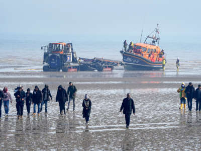 A group of people thought to be migrants are guided up the beach after being brought in to Dungeness, Kent, onboard a lifeboat following an incident in the English Channel on March 24, 2022.