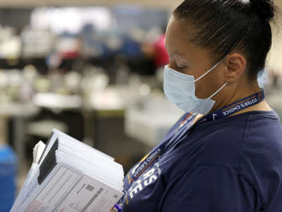 A worker sorts through a stack of mail-in-ballots before putting them into a sorting machine at the Santa Clara County Registrar of Voters on September 14, 2021, in San Jose, California.