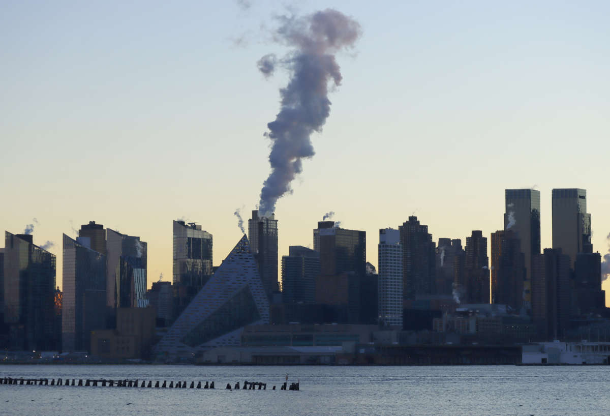 Emissions come out of a smokestack on the west side of Manhattan as the sun rises in New York City on January 16, 2022, as seen from Weehawken, New Jersey.