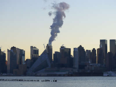 Emissions come out of a smokestack on the west side of Manhattan as the sun rises in New York City on January 16, 2022, as seen from Weehawken, New Jersey.