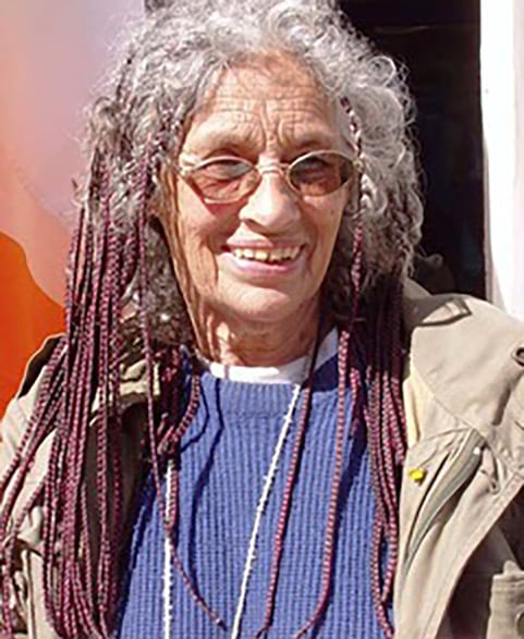 Portrait of a bespectacled woman with braids in her hair.