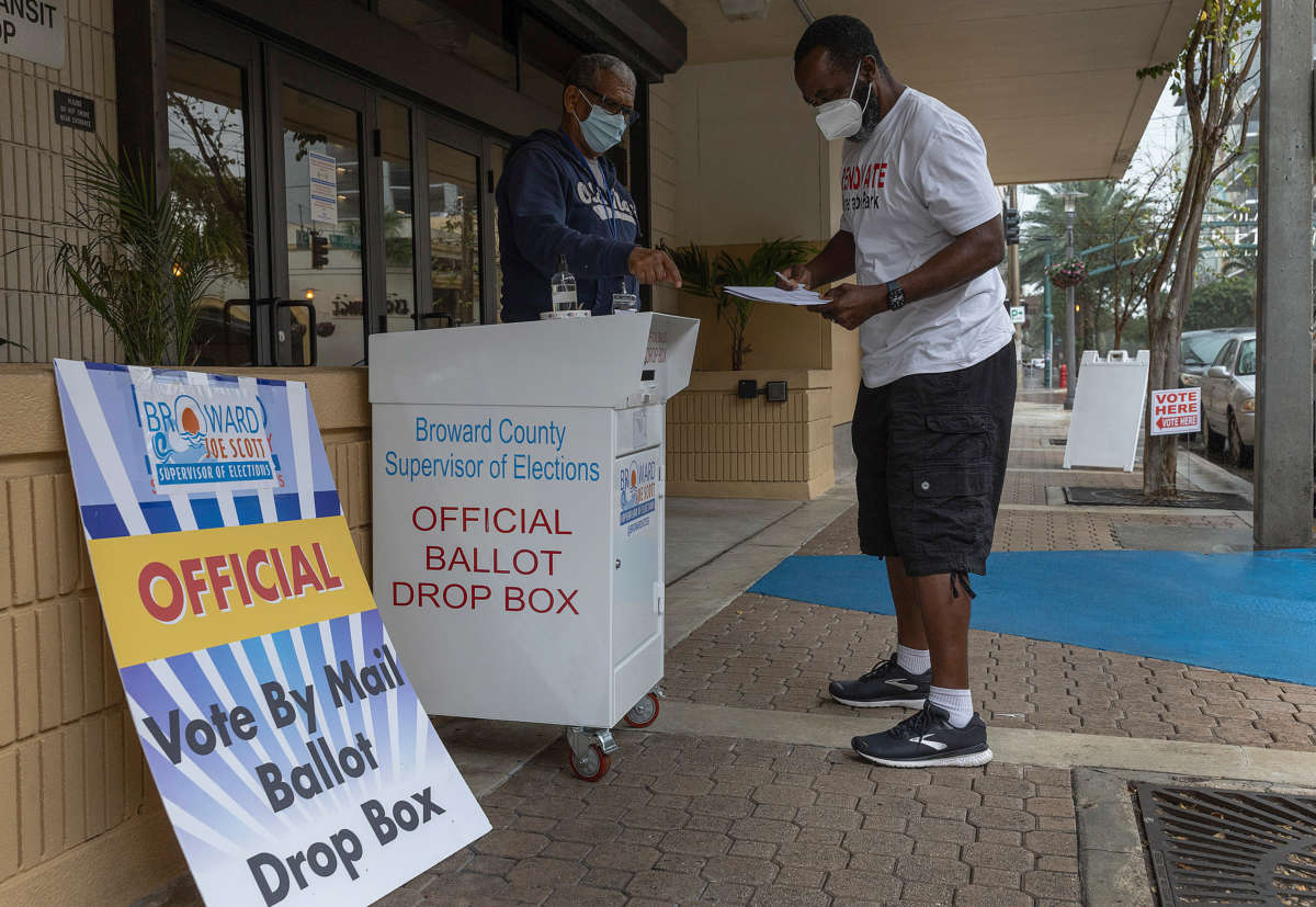 A voter prepares to place his ballot in a vote by mail ballot drop box on January 11, 2022, in Ft. Lauderdale, Florida.