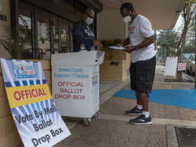 A voter prepares to place his ballot in a vote by mail ballot drop box on January 11, 2022, in Ft. Lauderdale, Florida.