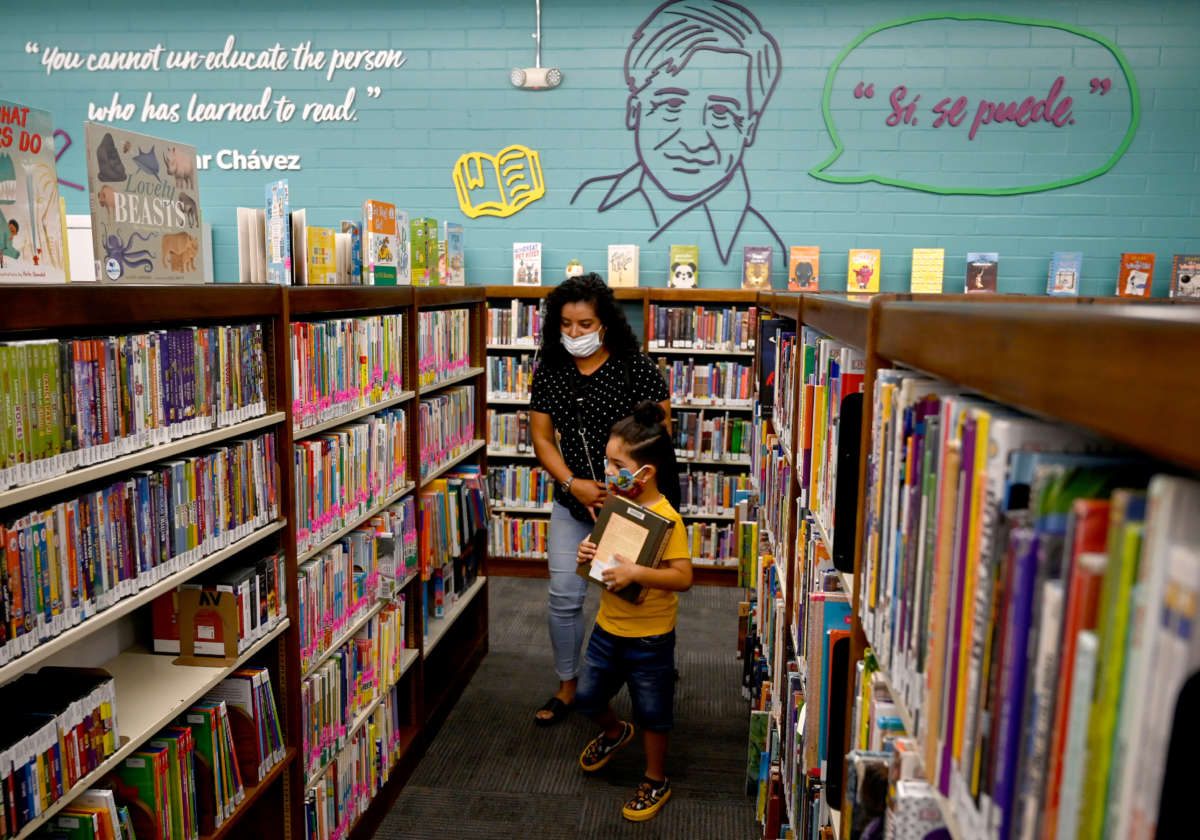 Liliana Real and Giovanni Garcia pick out books at the grand reopening of the Maywood Cesar Chavez Library in Maywood, California, on July 28, 2021.