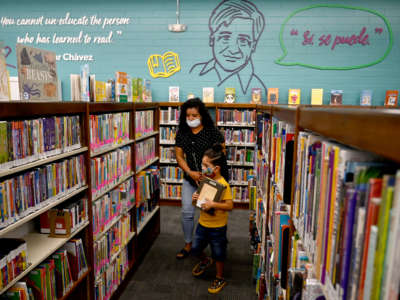Liliana Real and Giovanni Garcia pick out books at the grand reopening of the Maywood Cesar Chavez Library in Maywood, California, on July 28, 2021.