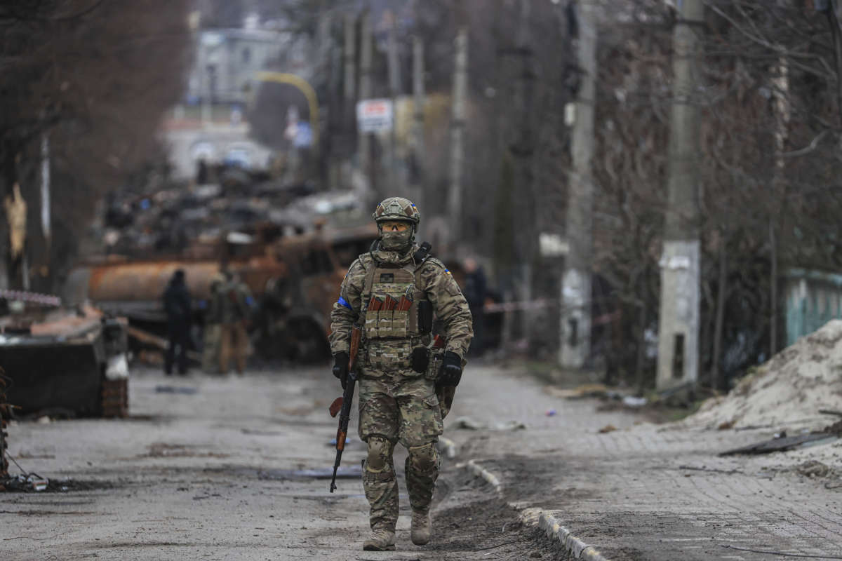 A soldier in uniform stands alone in the middle of a street
