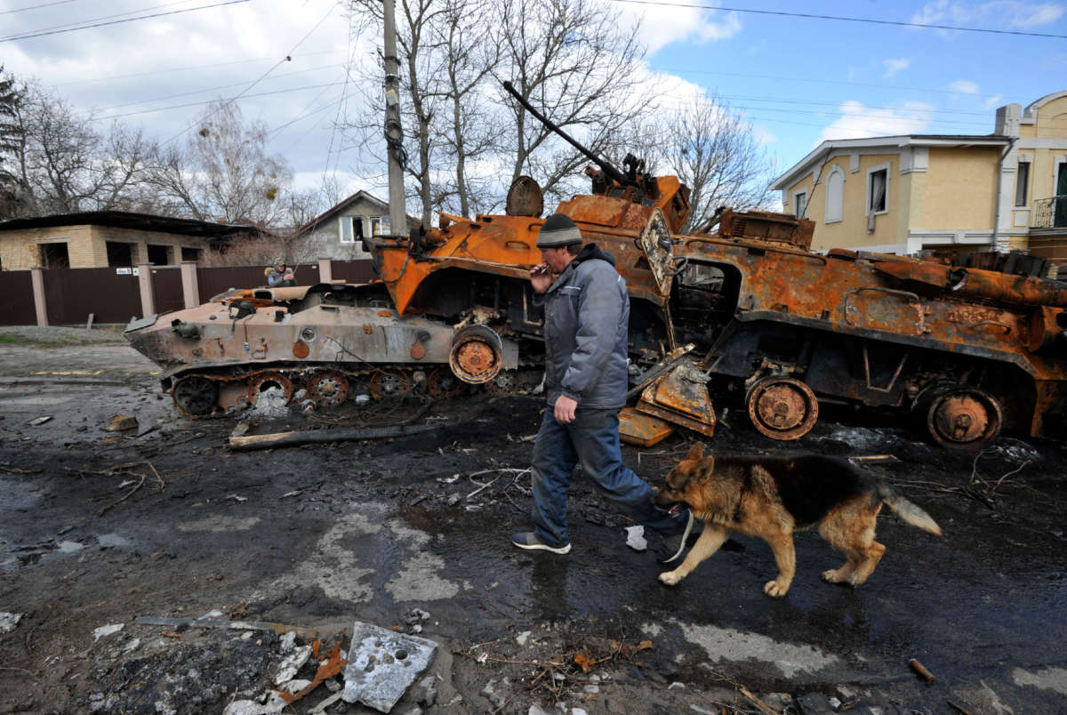 A man walks by with his dog past destroyed military equipment of the Russian army against the background of severe destruction in Bucha, Ukraine, on April 4, 2022.