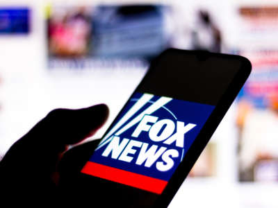 Hand holding cell phone with Fox News logo on display