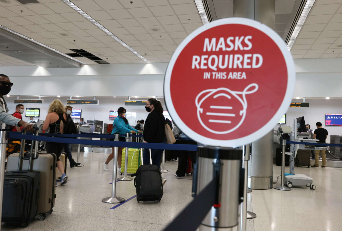 A sign reading, 'masks required in this area,' is seen as travelers prepare to check-in for their flight at the Miami International Airport on February 1, 2021 in Miami, Florida.