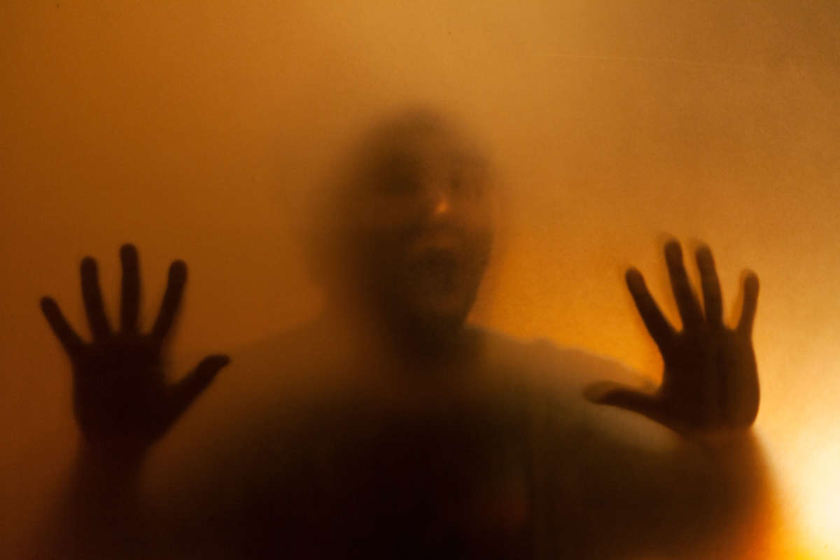 Man screaming behind blurred glass