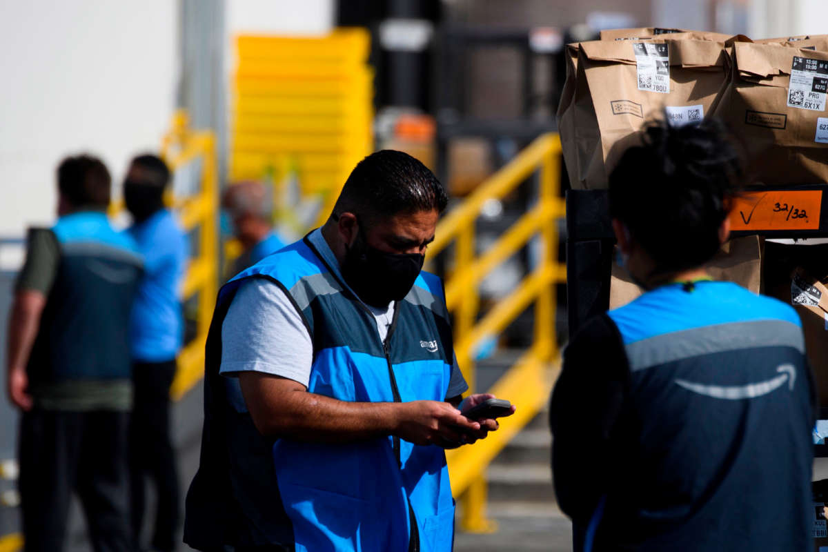 An Amazon delivery driver scans bags of groceries while loading a vehicle outside of a distribution facility on February 2, 2021, in Redondo Beach, California.