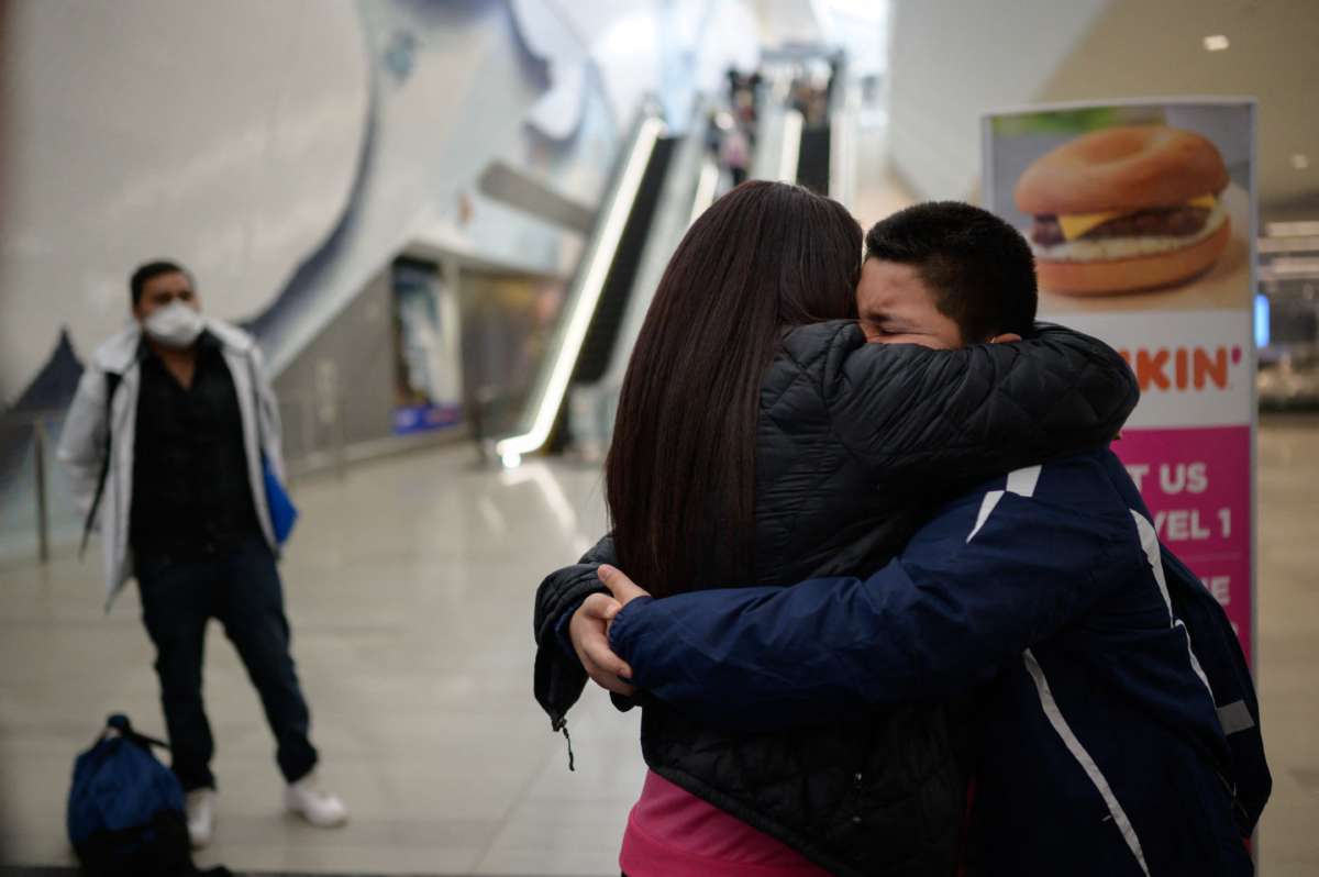 A boy embraces his mother in an airport
