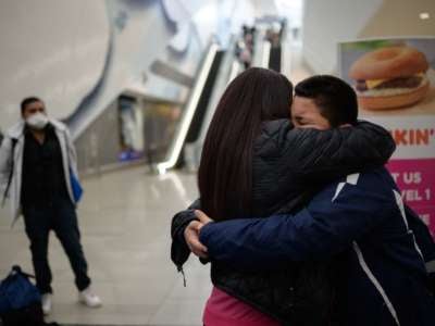 A boy embraces his mother in an airport