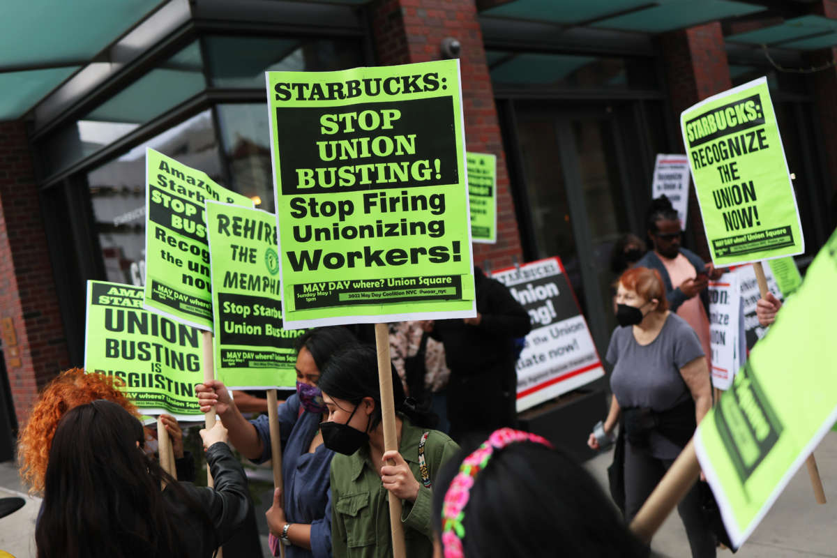 People hold signs while protesting in front of Starbucks on April 14, 2022, in New York City.