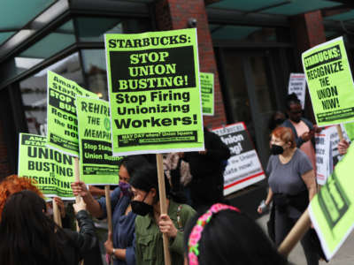 People hold signs while protesting in front of Starbucks on April 14, 2022, in New York City.