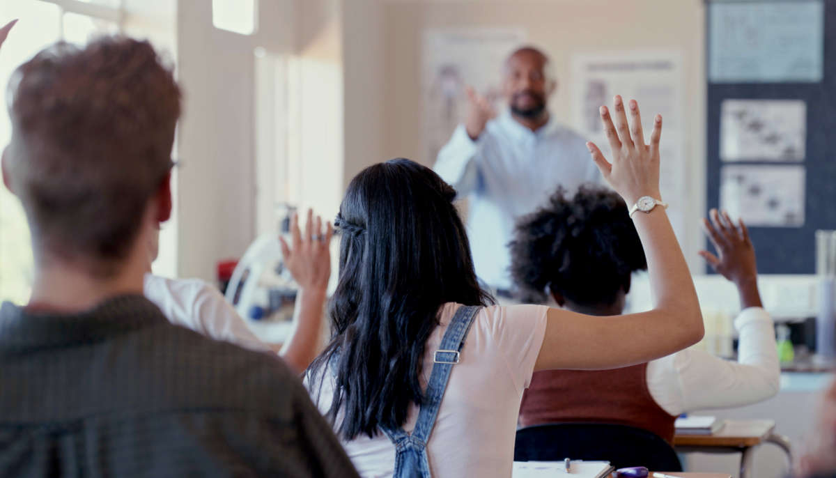 Students raise hands in class for teacher