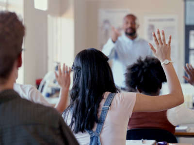 Students raise hands in class for teacher