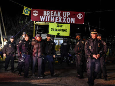 New York City police officers detain members of environmental activist group Extinction Rebellion as they set up a blockade in front of the New York Times printing plant in the Flushing neighborhood of Queens on April 22, 2022, in New York City.