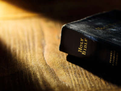 Holy Bible on wooden table with light shining on it