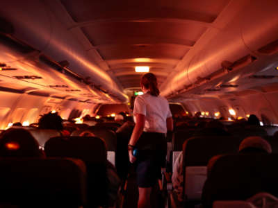 A flight attendant walks through an airplane before the plane's descent into the Dallas/Fort Worth International Airport on November 24, 2021, in Dallas, Texas.