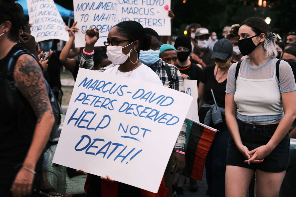 Protesters holding a sign that reads "Marcus-David Peters Deserved HELP Not DEATH!!" at a demonstration on July 28, 2020, in Richmond, Virginia. Marcus-David was a 24-year-old Black man who was shot and killed by a Richmond police officer on May 14, 2018, while experiencing a mental health crisis.