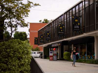 A person wears a face mask as they walk past the University Bookstore at the California State University Long Beach (CSULB) campus on August 11, 2021, in Long Beach, California.